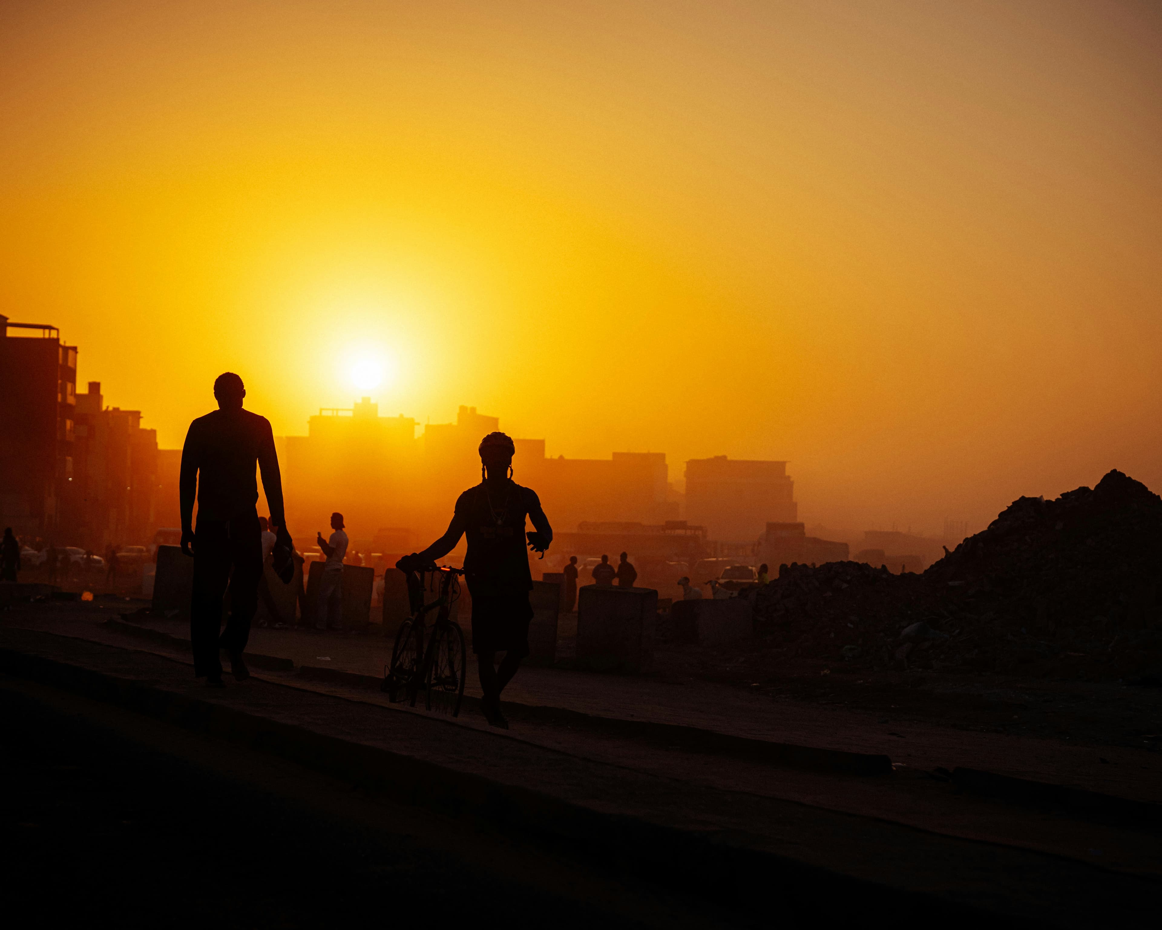 Des personnes marchent à Dakar au coucher du soleil